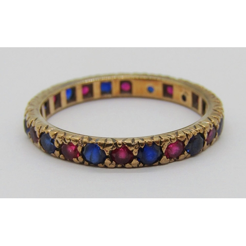 391 - Yellow metal eternity ring set with blue and pink gems (possibly synthetic), size Q/R, 2.3g