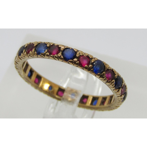 391 - Yellow metal eternity ring set with blue and pink gems (possibly synthetic), size Q/R, 2.3g