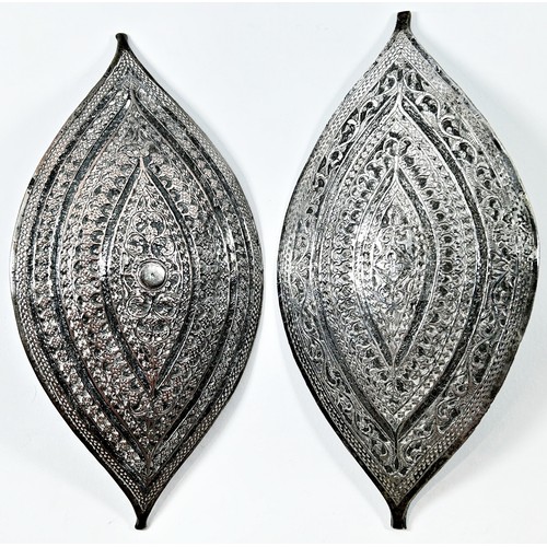 294 - Two Malay Metalware buckles both richly engraved in similar designs, 21 cm x 10 cm together with ano... 