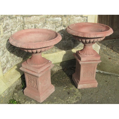 1024 - A pair of cast composition stone garden urns with faux terracotta finish, the squat circular lobed b... 