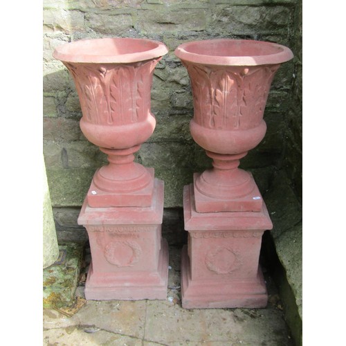 1030 - A pair of cast composition stone trumpet shaped garden urns with faux terracotta finish, relief deta... 