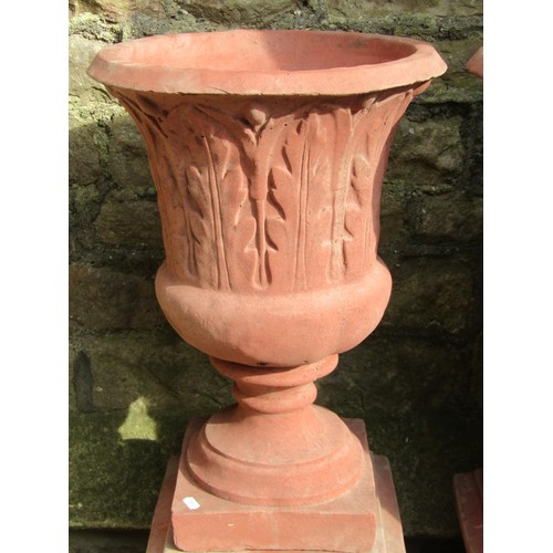 1030 - A pair of cast composition stone trumpet shaped garden urns with faux terracotta finish, relief deta... 