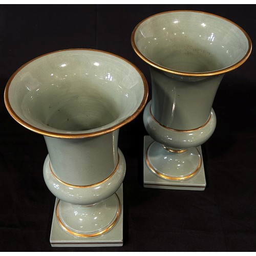 104 - A pair of celadon glazed campana shaped vases with gilded bands, 28cm high