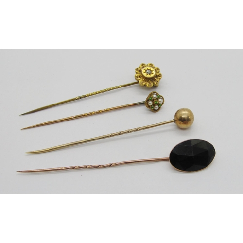 411 - Four antique yellow metal stick pins to include a Victorian diamond set example, a quatrefoil pearl ... 