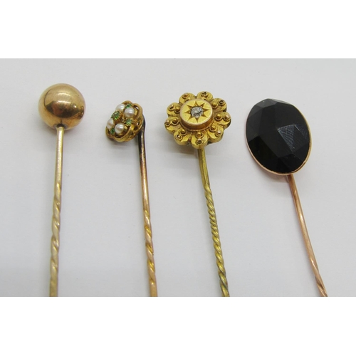 411 - Four antique yellow metal stick pins to include a Victorian diamond set example, a quatrefoil pearl ... 