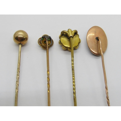 411 - Four antique yellow metal stick pins to include a Victorian diamond set example, a quatrefoil pearl ... 