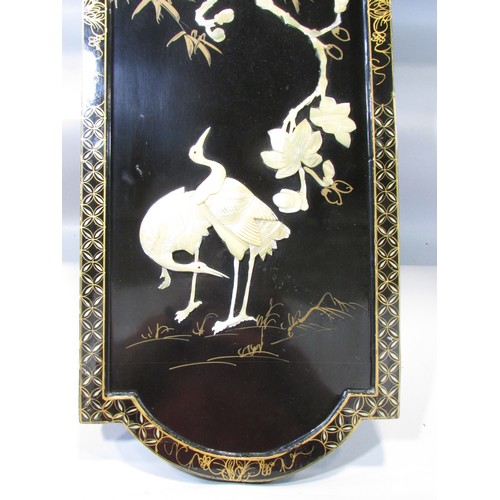 620 - A Japanese decorative black lacquered panel with cranes and cherry blossom in Mother of Pearl relief... 