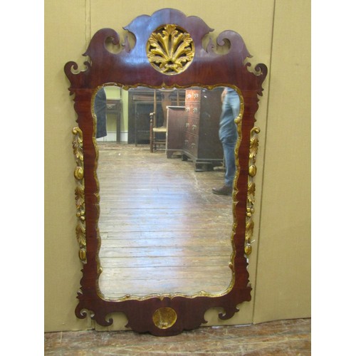 1633 - A Georgian Mahogany wall mirror with shaped and fretted outline and further gilded detail, 63cm wide... 