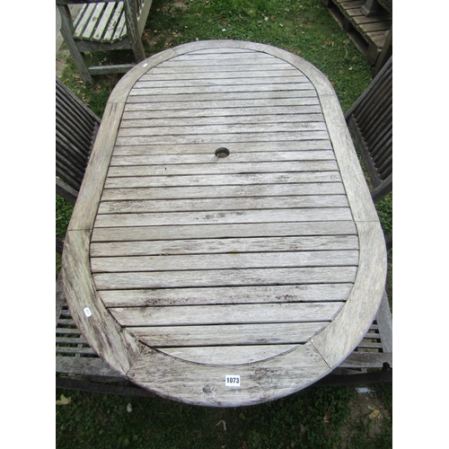 1073 - A weathered teak garden table of oval slatted form, raised on X framed supports, together with four ... 