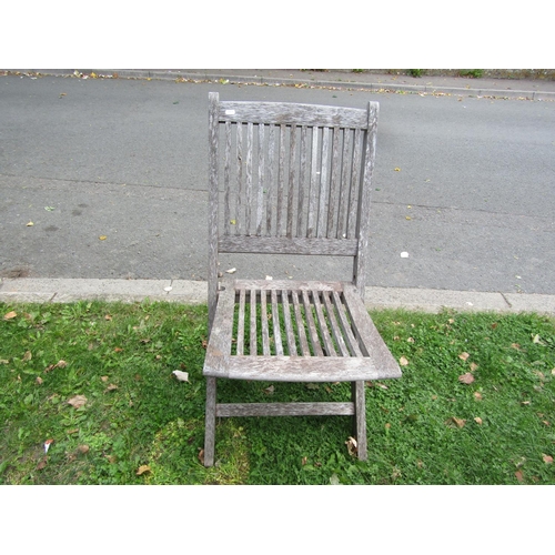 1073 - A weathered teak garden table of oval slatted form, raised on X framed supports, together with four ... 