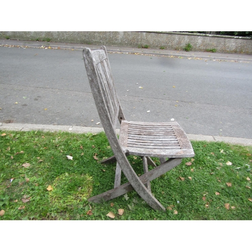 1073 - A weathered teak garden table of oval slatted form, raised on X framed supports, together with four ... 