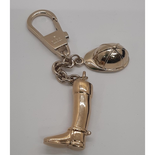 35 - Gucci  keyring featuring a riding boot and hat in gold metalwork with monogrammed cloth bag and box.... 