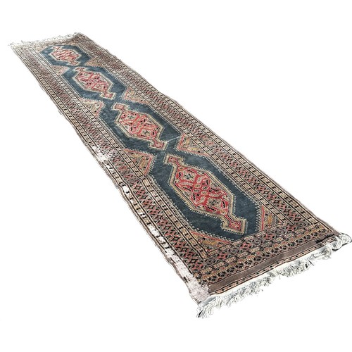 1652 - A Persian runner with four extended lozenges on a pale blur ground, with a signature 370cm by 80cm