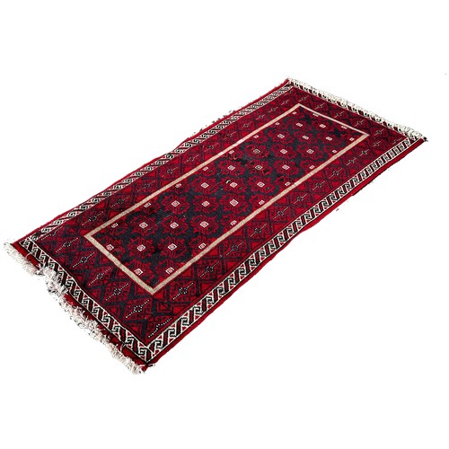 1651 - A small Afghan runner with a central geometric panel on a predominantly red ground 180cm x 87cm appr... 