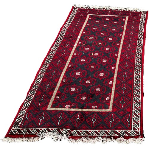 1651 - A small Afghan runner with a central geometric panel on a predominantly red ground 180cm x 87cm appr... 