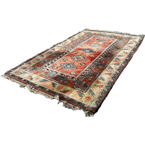 1656 - A Turkey carpet with a central panel with five diamond medallions on a pink and light blue ground, 3... 