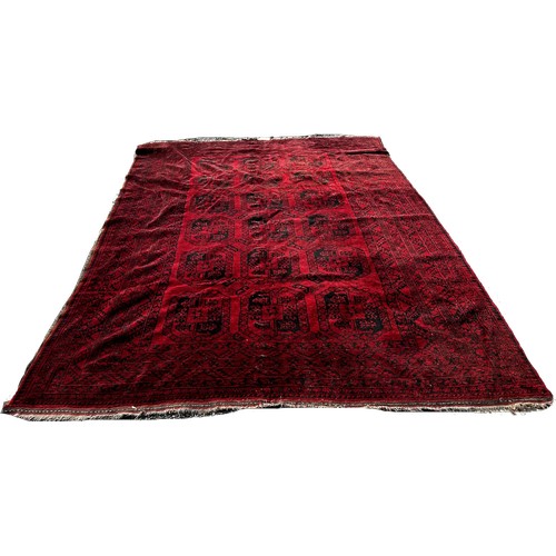 1665 - A Bokhara type carpet with three rows of elephant foot medallions on a red carpet 220cm by 312cm app... 