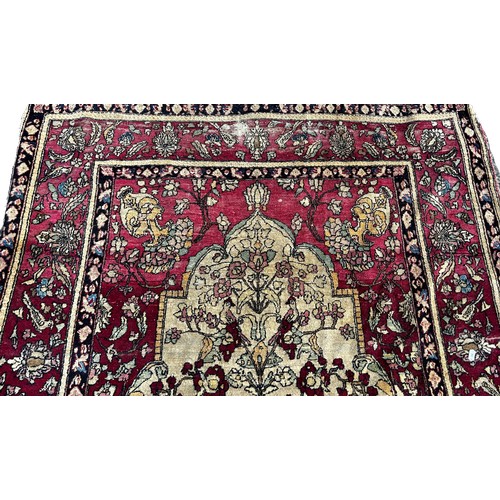 1673 - A fine old Persian carpet with a central vase of flowers set in a prayer arch with further floral de... 