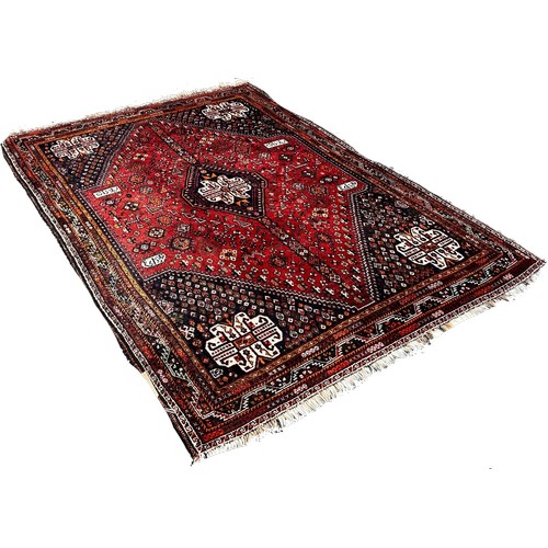 1678 - A Middle Eastern carpet with a central diamond lozenge on a red floral field, 239cm x 160cm approxim... 