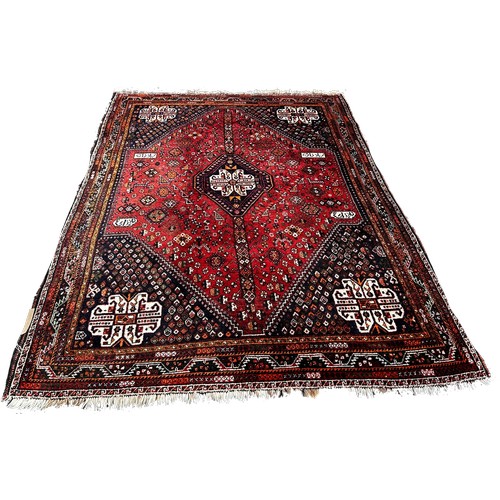 1678 - A Middle Eastern carpet with a central diamond lozenge on a red floral field, 239cm x 160cm approxim... 