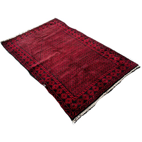 1690 - A Baluchi rug with an all over small red and black diamond, 140cm x 90cm approximately