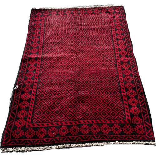 1690 - A Baluchi rug with an all over small red and black diamond, 140cm x 90cm approximately