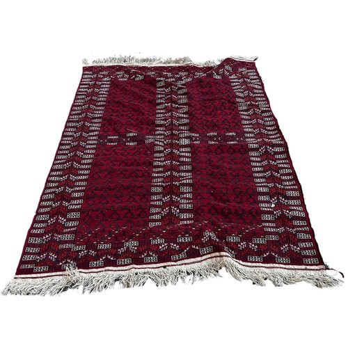 1696 - A Turkoman style rug with geometric patterns on a red ground, 200cm x 125cm.