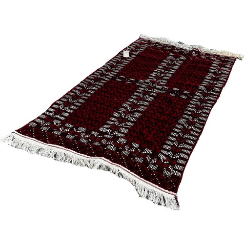 1696 - A Turkoman style rug with geometric patterns on a red ground, 200cm x 125cm.