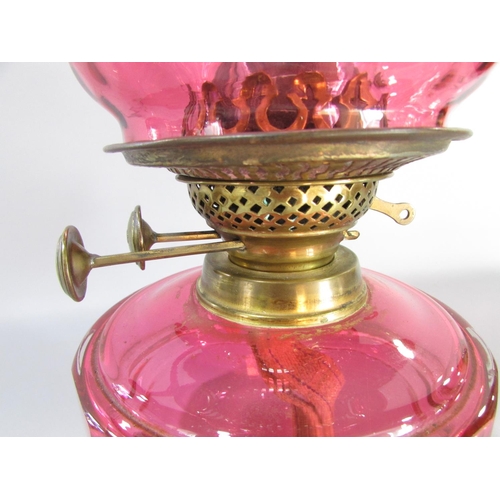 605 - A Victorian brass wall bracketed oil lamp with a crimped Cranberry glass shade and font.