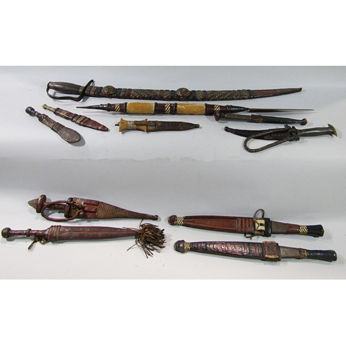 712 - Eleven East African Swords and daggers generally within similar decorated leather scabbards