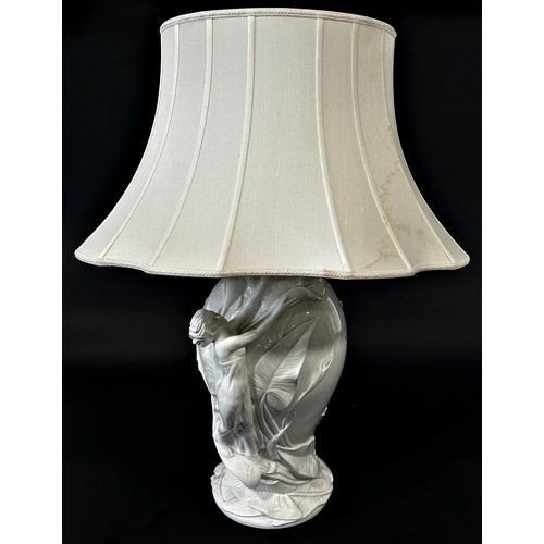 745 - A white porcelain art nouveau style table lamp with female and floral decoration, with pleated shade... 