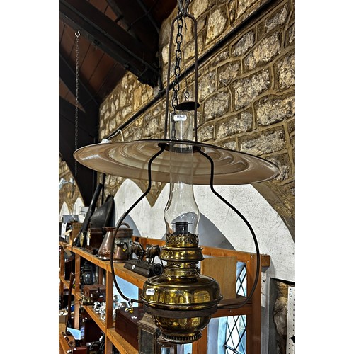 764 - A ceiling hanging brass oil lamp with a disc enamel shade.