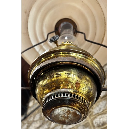 764 - A ceiling hanging brass oil lamp with a disc enamel shade.