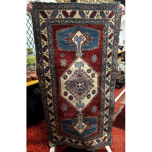 1697 - A Kazak type carpet with an extended lozenge medallion on a red ground, 175cm x90cm approximately