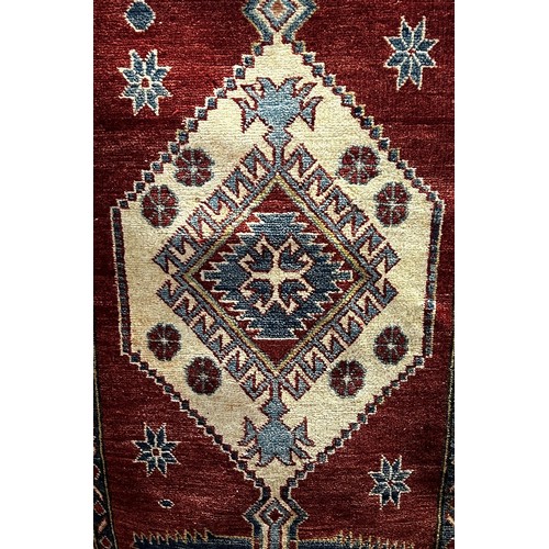 1697 - A Kazak type carpet with an extended lozenge medallion on a red ground, 175cm x90cm approximately