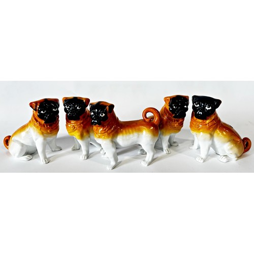 9 - A collection of five 19th century German porcelain pugs, four sitting and one standing