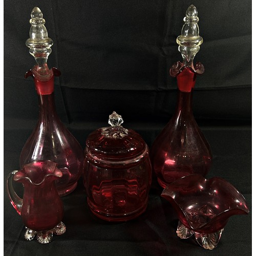 162 - A pair of Victorian cranberry glass decanters, with a similar sugar bowl, jug and a lidded jar.