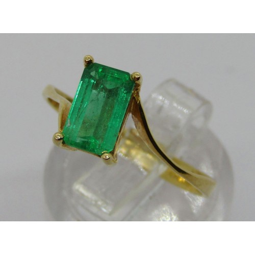 238 - 18k emerald-cut emerald crossover ring, the stone 8 x 5mm approx, size O, 2.5g