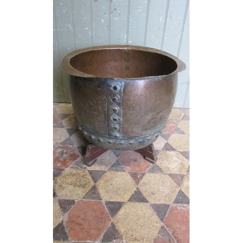 1052 - An antique copper cauldron with flared rim and pop rivetted banded seams, raised on a later bespoke ... 