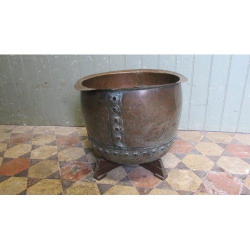 1052 - An antique copper cauldron with flared rim and pop rivetted banded seams, raised on a later bespoke ... 