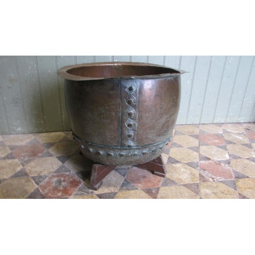 1052 - An antique copper cauldron with flared rim and pop rivetted banded seams, raised on a later bespoke ... 