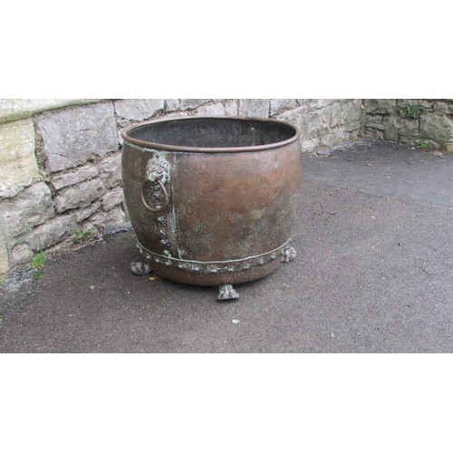 1064 - An antique copper cauldron/log bin with pop rivetted seams, lions mask and ring handles and paw feet... 