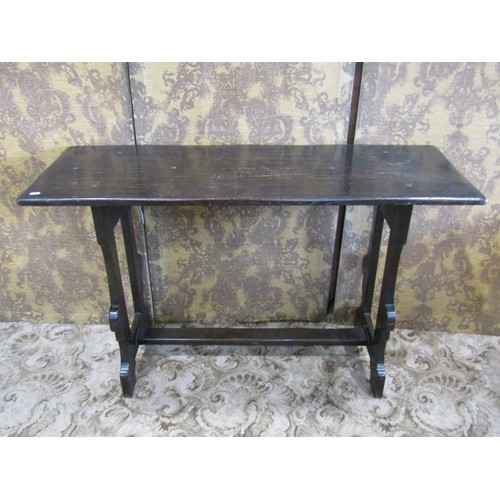 1129 - A dark stained oak table, the rectangular top raised on shaped supports united by a central through ... 