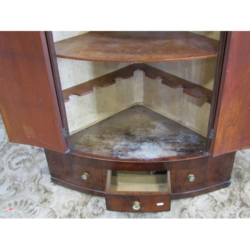 1138 - An early 19th century mahogany bow fronted hanging corner cupboard enclosed by two doors over one re... 