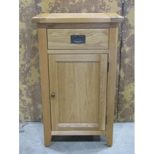 1194 - A contemporary oak free standing side cupboard partially enclosed by a panelled door beneath a friez... 