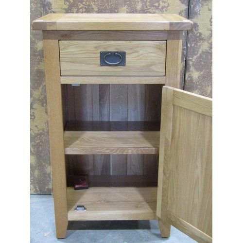 1194 - A contemporary oak free standing side cupboard partially enclosed by a panelled door beneath a friez... 