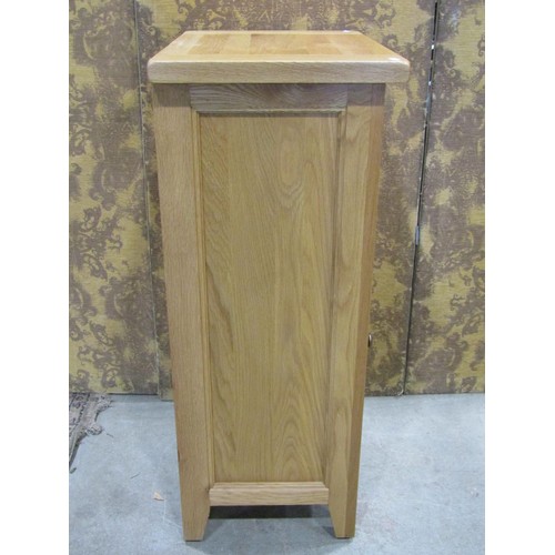 1194 - A contemporary oak free standing side cupboard partially enclosed by a panelled door beneath a friez... 