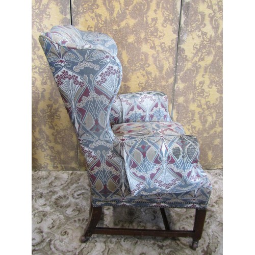 1251 - A Georgian style wing chair with shaped outline and stylised floral upholstery raised on square cut ... 