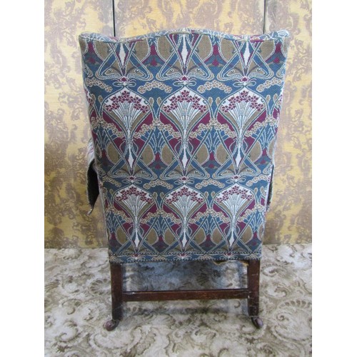 1251 - A Georgian style wing chair with shaped outline and stylised floral upholstery raised on square cut ... 