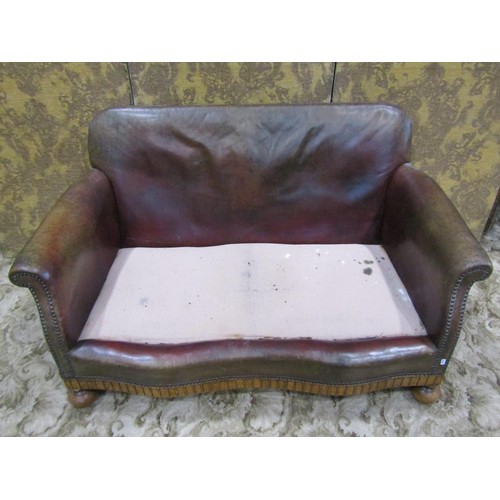 1275 - An early 20th century low two seat sofa upholstered in brown leather with studded detail, swept and ... 